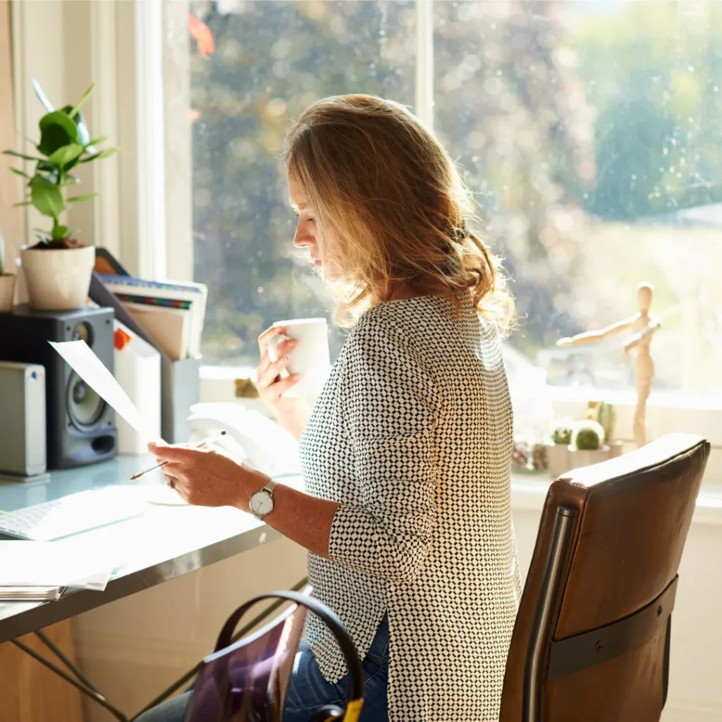 Woman reviewing formal documents at home office desk with natural light